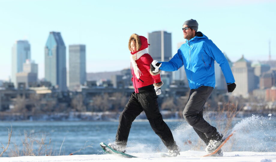 Happy,Couple,Snowshoeing,Running,In,Montreal,With,Cityscape,Skyline,And